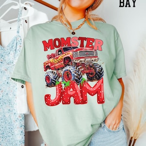 May include: A light green t-shirt with a red monster truck graphic and the text "Momster Jam" in red letters with strawberry accents.