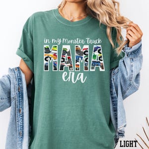 Puede incluir: Una camiseta verde claro con el texto "in my monster truck mama era" impreso en blanco. La palabra "mama" est&aacute; formada por im&aacute;genes de monster trucks.