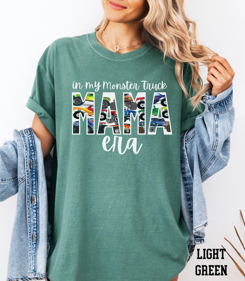 Puede incluir: Una camiseta verde claro con el texto "in my monster truck mama era" impreso en blanco. La palabra "mama" est&aacute; formada por im&aacute;genes de monster trucks.