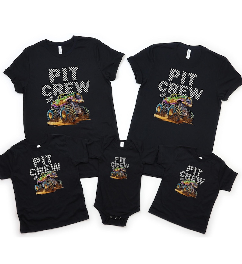 May include: Black t-shirts and a onesie with a colorful monster truck graphic. The text "PIT CREW" is printed above the truck in a checkered pattern. The monster truck is depicted in shades of green, purple, blue, and orange.