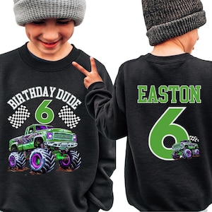 Op de afbeelding: Zwart sweatshirt met een groene monstertruckafbeelding, het nummer 6 en de tekst "BIRTHDAY DUDE" op de voorkant. De achterkant toont de naam "EASTON" en het nummer 6 in groen. Een leuk ontwerp voor een verjaardag.