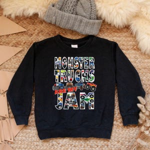 Puede incluir: Sudadera negra de manga larga con un estampado gr&aacute;fico de camiones monstruo y el texto "Monster Trucks Are My Jam".