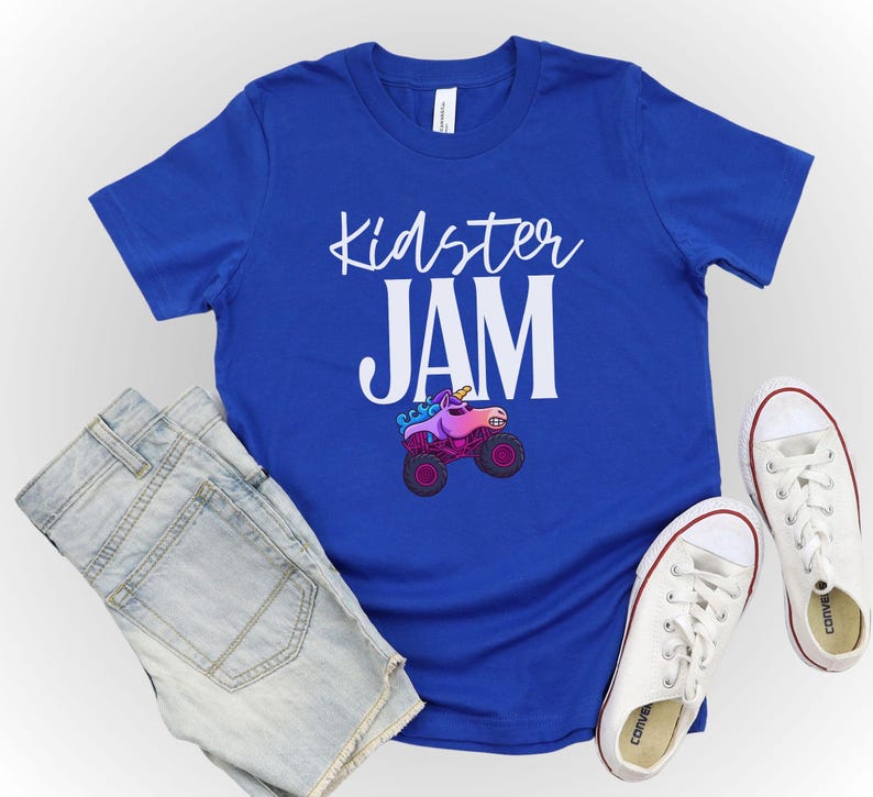 May include: A royal blue t-shirt with the words "Kidster JAM" in white script. A cartoon monster truck with a unicorn head is featured below the text. The shirt is paired with denim shorts and white canvas sneakers.