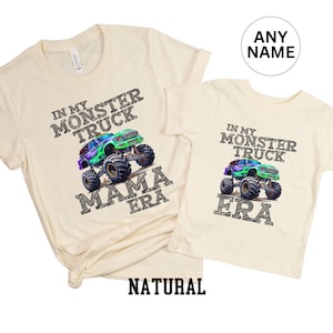 May include: Two cream-coloured t-shirts. One adult-sized shirt with the text "IN MY MONSTER TRUCK MAMA ERA" and a graphic of a monster truck. The other is a child-sized shirt with the text "IN MY MONSTER TRUCK ERA" and a monster truck graphic.