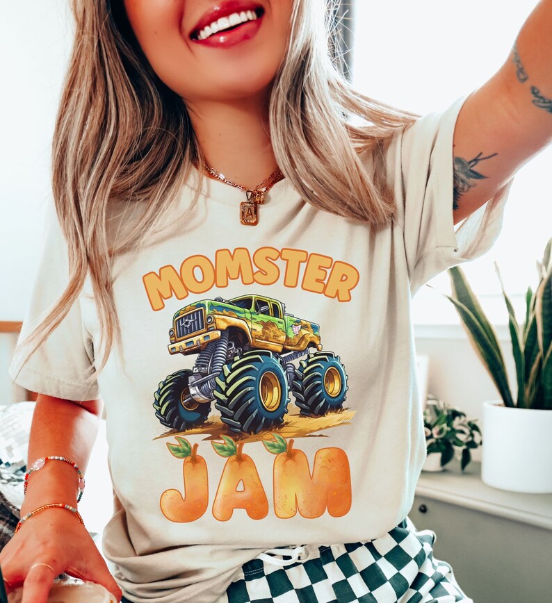 May include: A white t-shirt with a green and yellow monster truck graphic and the text "Momster Jam" in orange letters.
