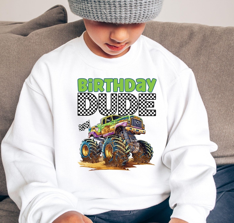 May include: White sweatshirt with a green and black monster truck graphic and the text "Birthday Dude" in green and black checkered lettering.