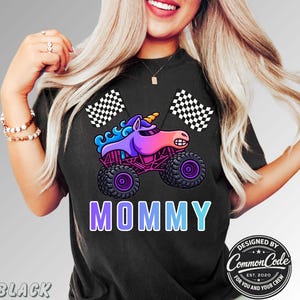 May include: Black t-shirt featuring a colorful graphic of a unicorn monster truck with the word "MOMMY" in a gradient font. Two checkered flags are on either side of the truck. The design includes the text "DESIGNED BY COMMON CODE EST. 2020 FOR YOU AND YOUR CREW."