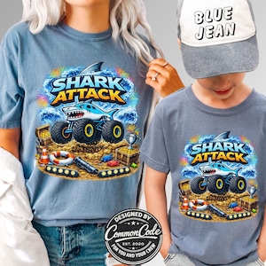 Pictured is a Mother and Son wearing blue t-shirts which sat SHARK ATTACK with a cartoon shark monster truck with beach nautical ocean background