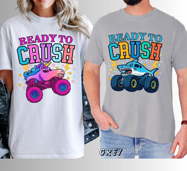 May include: White and grey t-shirts with the text "READY TO CRUSH". One shirt features a unicorn monster truck, the other a shark monster truck. Both designs have colorful graphics and star accents.