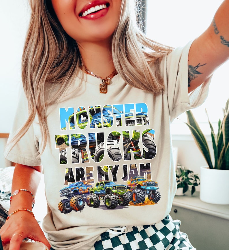 May include: A beige t-shirt with the text "Monster Trucks Are My Jam" printed on the front. The text is surrounded by images of monster trucks.