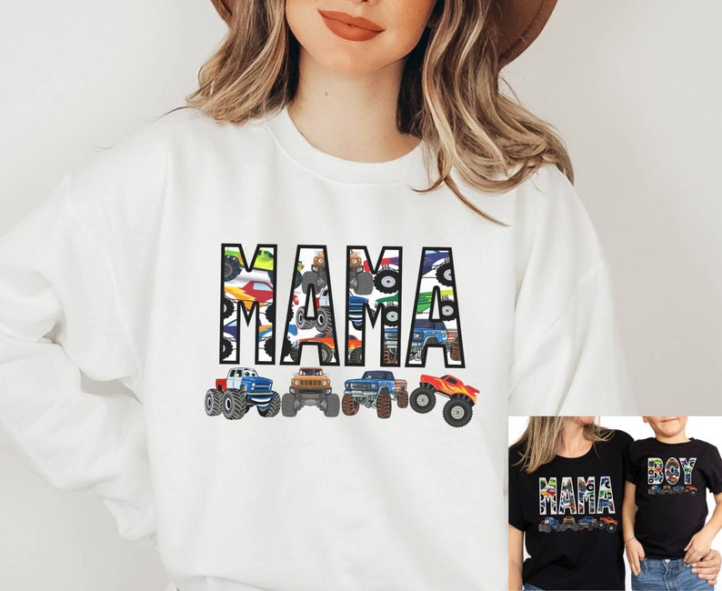 May include: White sweatshirt with the word "MAMA" in large, black block letters filled with colorful monster truck designs. Below the word are five monster truck illustrations. A smaller image shows a matching shirt.