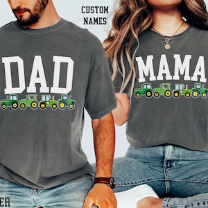 Puede incluir: Dos camisetas grises con texto blanco y gráficos de tractores verdes. Una camiseta dice "DAD" y la otra dice "MAMA". Los tractores están debajo del texto. Las camisetas las llevan dos personas. El texto "CUSTOM NAMES" está arriba.