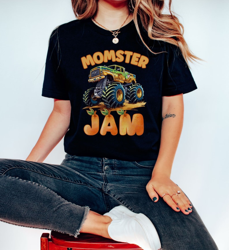 woman model is wearing a black t-shirt with the words "Momster Jam" with a green muddy Monster Truck. Jam Letters are Pear Gold Peachy Colored and shaped.  Personalized any Name Family Matching Monster Truck Jam Pit Party Theme.