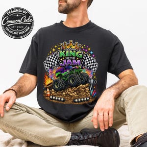 Peut inclure: T-shirt noir avec un motif color&eacute; d'un monster truck et le texte "KING OF THE JAM". Le design comprend des drapeaux &agrave; damier, une couronne et le logo Common Code.
