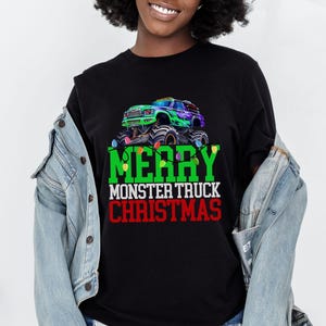 Puede incluir: Camiseta negra con un gr&aacute;fico de cami&oacute;n monstruo verde y el texto "Feliz Navidad del cami&oacute;n monstruo".