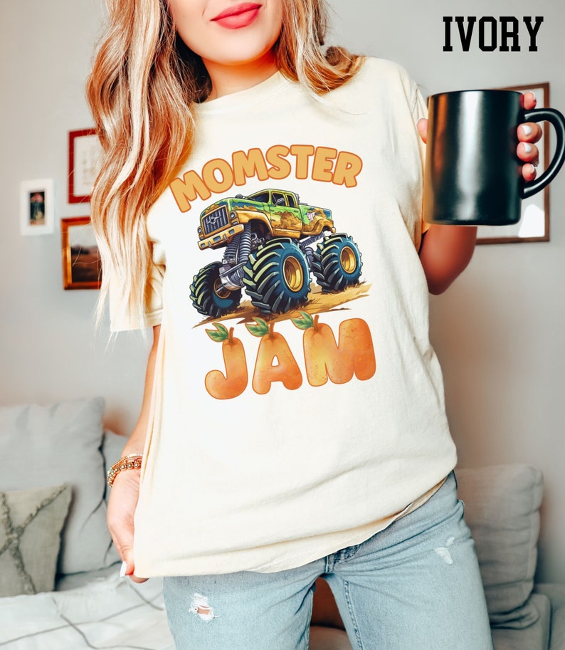May include: A white t-shirt with a green monster truck graphic and the text "Momster Jam" in orange letters. The truck is driving over orange peaches.