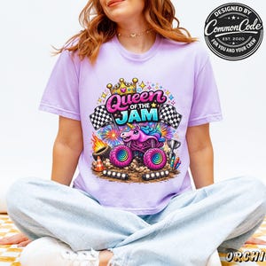 Peut inclure: Un t-shirt lilas avec un graphisme color&eacute; d'un monster truck avec un design de licorne et le texte "Queen of the Jam". Le design comprend des drapeaux &agrave; damier, des feux d'artifice et les mots "Designed by Common Code".