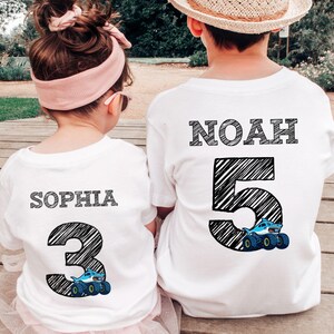 Op de afbeelding: Twee witte T-shirts. E&eacute;n shirt heeft de naam "SOPHIA" boven een groot nummer "3" met een monster truck-afbeelding. De andere heeft "NOAH" boven een groot nummer "5" met een monster truck-afbeelding. De tekst en nummers zijn zwart.
