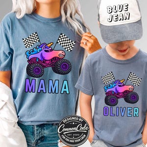 May include: Matching blue t-shirts with a monster truck unicorn graphic and checkered flags. One shirt says "MAMA" and the other says "OLIVER". A gray baseball cap with "BLUE JEAN" is worn by the child. Designed by Common Code.