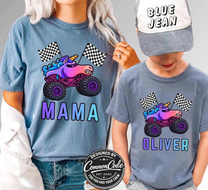 May include: Matching blue t-shirts with a monster truck unicorn graphic and checkered flags. One shirt says "MAMA" and the other says "OLIVER". A gray baseball cap with "BLUE JEAN" is worn by the child. Designed by Common Code.