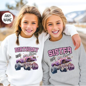 Pu&ograve; includere: Due ragazze indossano felpe abbinate con una grafica di un monster truck rosa. Una felpa dice "Birthday Jam" e l'altra dice "Sister Jam". Entrambe le felpe hanno il nome "Sophia" stampato su di esse.