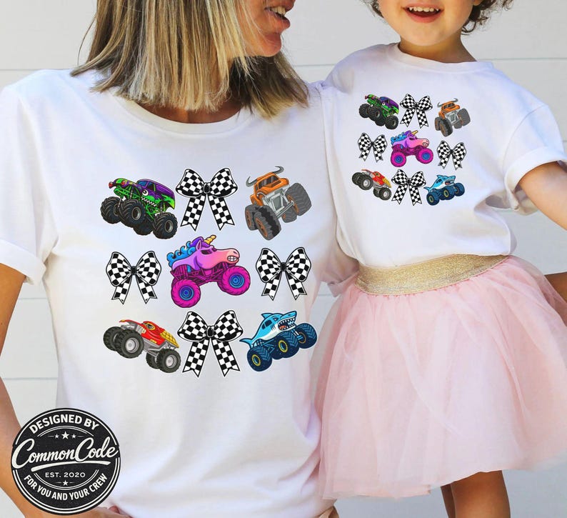 May include: White t-shirts with colorful monster truck graphics and checkered bows. The shirts feature various monster truck designs in green, purple, orange, pink, red, and blue. The bottom of the shirt has a circular logo that says "DESIGNED BY COMMON CODE EST. 2020 FOR YOU AND YOUR CREW."