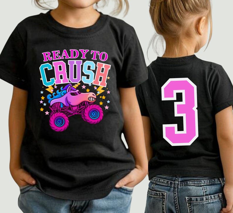 Pode incluir: T-shirt preto com a frase "READY TO CRUSH" e um desenho animado de um monster truck com cabe&ccedil;a de unic&oacute;rnio. O caminh&atilde;o &eacute; rosa e roxo com rodas azuis. O n&uacute;mero "3" est&aacute; nas costas da camisa.