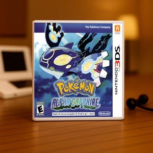 Peut inclure: Boîtier de jeu Nintendo 3DS pour Pokémon Alpha Sapphire. Le boîtier présente un design bleu et blanc avec une illustration de Kyogre. Le titre du jeu est en jaune et bleu. L'évaluation ESRB est visible.