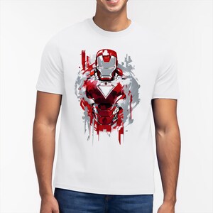Puede incluir: Camiseta blanca con una ilustraci&oacute;n estilizada de la armadura de Iron Man en rojo y plata. El dise&ntilde;o tiene un efecto de salpicaduras de pintura con acentos rojos y grises, creando un aspecto din&aacute;mico. La camiseta es de cuello redondo cl&aacute;sico.