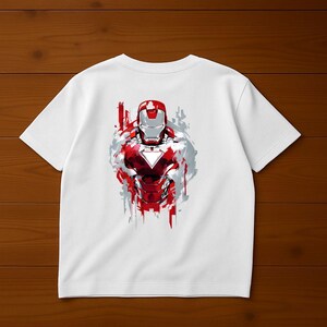 Puede incluir: Camiseta blanca con un dise&ntilde;o rojo, plateado y blanco de Iron Man. El dise&ntilde;o est&aacute; estilizado con efectos de pinceladas, mostrando el casco y la placa del pecho del superh&eacute;roe. La camiseta es de material suave.