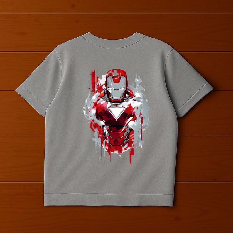 Puede incluir: Una camiseta gris con un gr&aacute;fico de la armadura de Iron Man en rojo, blanco y plateado. El dise&ntilde;o tiene un estilo art&iacute;stico desgastado con trazos de pintura, creando un aspecto din&aacute;mico y audaz. La camiseta es de manga corta.