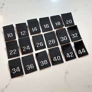 May include: Black fabric size labels with white numbers ranging from 10 to 44.