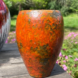 May include: Orange and black ceramic vase with a mottled glaze.