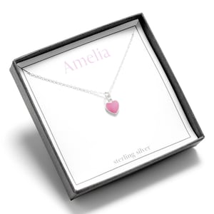 May include: A silver necklace with a pink heart pendant in a gift box. The box has the name "Amelia" and the words "sterling silver" printed on it.
