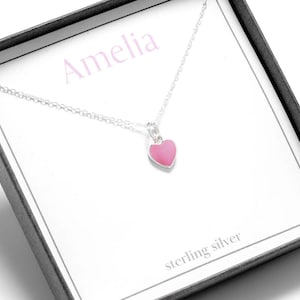 May include: A silver necklace with a pink heart pendant. The necklace is in a box with the name Amelia and the words "sterling silver" written on it.