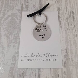 May include: Silver keychain with a soccer ball charm, a charm with the number 21, and a charm with the name "Ben" on it. The keychain is on a white card with the text "handmade with love GG JEWELLERY & GIFTS".