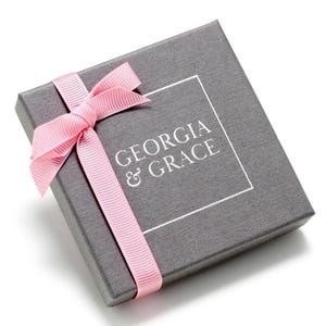 May include: A gray gift box with a pink ribbon and the text "GEORGIA & GRACE" printed on the top.