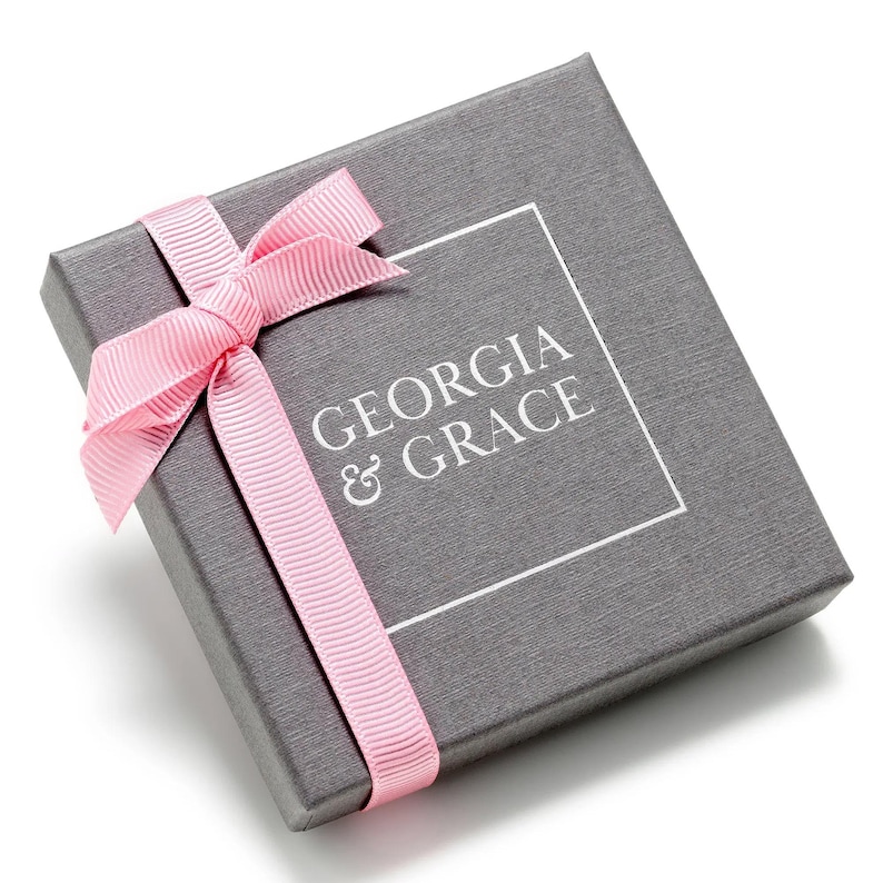 May include: A gray gift box with a pink ribbon and the text "GEORGIA & GRACE" printed on the top.