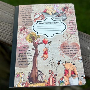 May include: Composition book featuring Winnie the Pooh and friends. The cover has quotes and illustrations of Pooh, Piglet, Tigger, Eeyore, and Rabbit. The book has a white label that says "COMPOSITION BOOK".