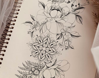 May include: A black and white line drawing of a floral tattoo design featuring a butterfly, a mandala, and two large flowers. The design is drawn on a white piece of paper.