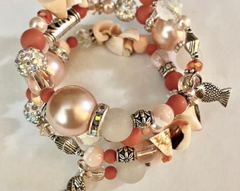 May include: A multi-strand bracelet with coral, white, and pink beads, shells, and silver charms. The bracelet features a seahorse and a fish charm.
