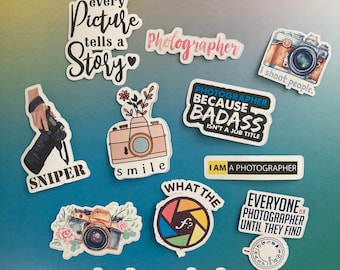 May include: A collection of photography-themed stickers with various designs and text. The stickers feature cameras, floral accents, and phrases like "Every Picture Tells a Story," "Photographer," and "I shoot people."