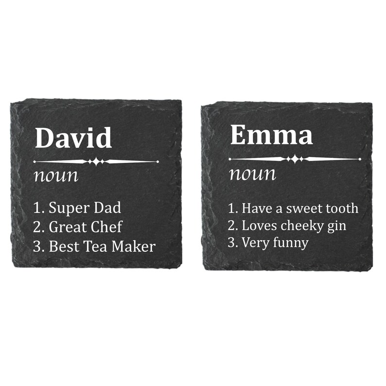 May include: Two black slate coasters with white text. The first coaster says "David noun 1. Super Dad 2. Great Chef 3. Best Tea Maker". The second coaster says "Emma noun 1. Have a sweet tooth 2. Loves cheeky gin 3. Very funny".
