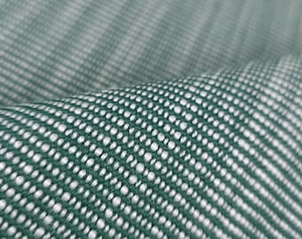 May include: Close-up of a textured fabric with a repeating pattern of white dots on a green background. The fabric is folded, creating a sense of depth and highlighting the weave. The material appears to be soft and possibly used for upholstery or clothing.