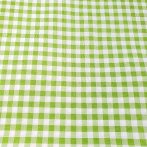 May include: A close-up of a green and white checkered fabric. The pattern consists of evenly spaced squares of light green and white, creating a classic gingham design. The fabric appears to be smooth and likely made of cotton or a similar material.