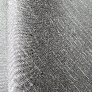 May include: Close-up of a textured fabric with a gradient of gray tones. The fabric has a subtle diagonal pattern with lighter, almost white, streaks running across the surface, creating a visual texture.