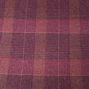 May include: Close-up of a woven fabric with a plaid pattern. The fabric features a mix of burgundy, brown, and black threads, creating a textured appearance. Thin red lines intersect the pattern, adding a subtle contrast. The overall design is a classic plaid.