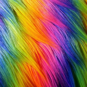 Può includere: Primo piano di un tessuto in pelliccia sintetica arcobaleno. Il tessuto è composto da fibre lunghe e morbide che sono tinti in una varietà di colori, tra cui blu, verde, giallo, arancione, rosso e viola.