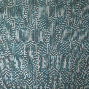 May include: Teal fabric with a repeating geometric pattern. The design features diamond and arrow-like shapes in a lighter, silvery color, creating a textured effect. The pattern is symmetrical and detailed, suitable for upholstery or decorative projects.