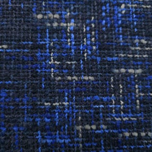 Può includere: Primo piano di un tessuto a trama fitta dall'aspetto strutturato. Il tessuto presenta un complesso motivo di fili intrecciati nelle tonalità blu navy, blu brillante e grigio, creando un design a griglia. La trama suggerisce un materiale resistente.